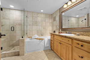 Bathroom featuring tile walls, vanity, tile patterned floors, and shower with separate bathtub