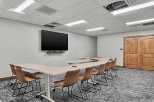 Rec room with dark colored carpet and a drop ceiling