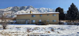 Snow covered rear of property with a mountain view