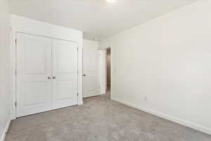 Unfurnished bedroom with light colored carpet and a closet