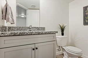 Bathroom featuring vanity, toilet, and hardwood / wood-style floors