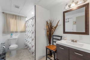 Bathroom featuring vanity, toilet, and a shower with shower curtain