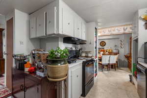 Kitchen featuring white cabinetry, black electric range oven, and dishwasher