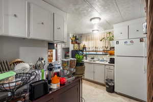 Kitchen with white refrigerator, white cabinetry, and sink