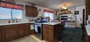 Kitchen with a stone fireplace, sink, stainless steel range with gas stovetop, and dark brown cabinetry