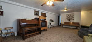 Living room with ceiling fan, a textured ceiling, and carpet