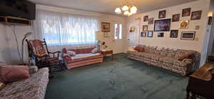 Living room with carpet floors, an inviting chandelier, and a textured ceiling