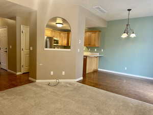 Living room featuring stylish gray colored carpet, with  smartly design access to kitchen and dining, and a chandelier