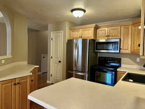 Kitchen with plenty of cupboards and counter space featuring sink, a textured ceiling, and appliances with stainless steel finishes