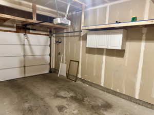 Garage featuring a garage door opener and shelves