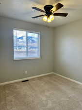 Cozy bedroom featuring ceiling fan, carpet floors, and a textured ceiling