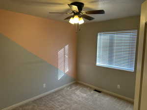 Spare room with light colored carpet, a textured ceiling, and ceiling fan