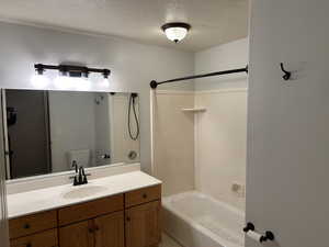 Full bathroom featuring shower / bathtub combination, vanity, toilet, and a textured ceiling