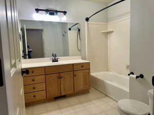 Full spacious bathroom featuring vanity, tile patterned flooring, bathtub / shower combination, and toilet with plenty of light