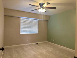 Primary bedroom with gray carpet, ceiling fan, and a textured ceiling