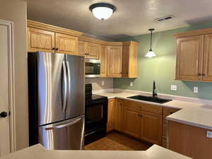 Kitchen featuring appliances with stainless steel finishes, decorative light fixtures, large farm style sink