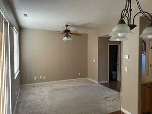 Carpeted spare room featuring ceiling fan and a textured ceiling