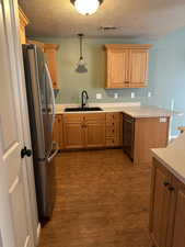 Kitchen with sink, stainless steel fridge, dark hardwood / wood-style flooring, decorative light fixtures, and kitchen peninsula