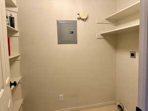 Laundry area featuring electric panel and electric dryer hookup and shelving