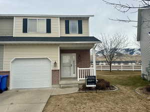 View of the bright  front of property including a fun porch with a mountain view, a garage, and a front lawn