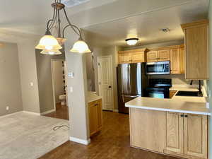 Kitchen from dining room thoughtfully designed with dark wood-type flooring, sink, decorative light fixtures, a textured ceiling, and appliances with stainless steel finishes