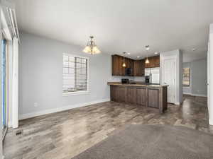 Kitchen with decorative light fixtures, a chandelier, light wood-type flooring, kitchen peninsula, and stainless steel appliances