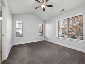 Carpeted empty room with lofted ceiling, plenty of natural light, and ceiling fan