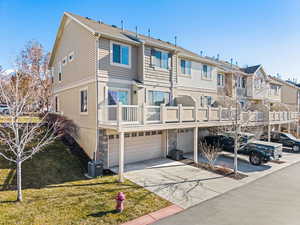 Exterior space featuring a garage, a balcony, a yard, and central AC