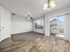 Empty room featuring ceiling fan with notable chandelier and hardwood / wood-style floors