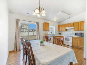 Dining room featuring lofted ceiling, sink, a chandelier, and light wood-type flooring