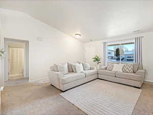 Living room with lofted ceiling and light colored carpet