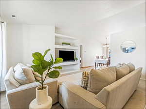 Living room featuring an inviting chandelier, lofted ceiling, and built in features