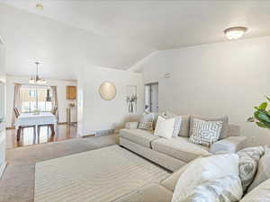 Carpeted living room with lofted ceiling and a chandelier