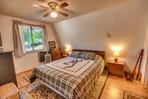 Bedroom featuring a textured ceiling, radiator heating unit, light hardwood / wood-style floors, and ceiling fan