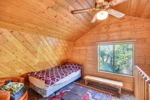 Bedroom with vaulted ceiling, ceiling fan, and wood ceiling