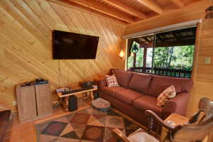 Living room featuring wood ceiling, beam ceiling, and wood walls