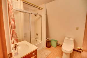 Full bathroom with vanity, parquet floors, shower / bath combination with glass door, and toilet