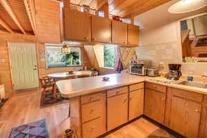 Kitchen with sink, light wood-type flooring, wooden ceiling, kitchen peninsula, and beam ceiling