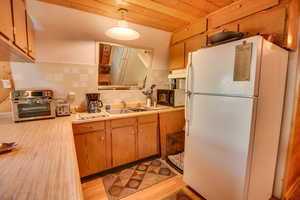 Kitchen featuring backsplash, light wood-type flooring, hanging light fixtures, and white fridge