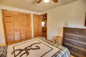 Bedroom featuring ceiling fan, a textured ceiling, and a closet