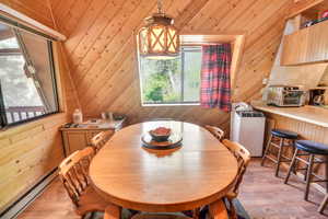 Dining room featuring a baseboard heating unit, light hardwood / wood-style floors, and wood walls