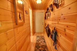 Hallway featuring light wood-type flooring, wood ceiling, and wood walls