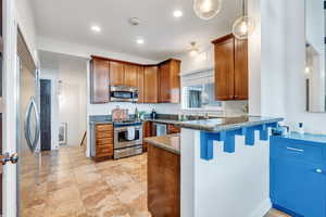 Kitchen with pendant lighting, sink, a kitchen bar, dark stone counters, and stainless steel appliances