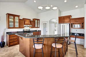 Kitchen with high vaulted ceiling, stainless steel appliances, a kitchen island with sink.