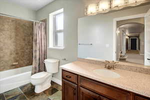 Full bathroom featuring vanity, shower / bath combination with curtain, and toilet