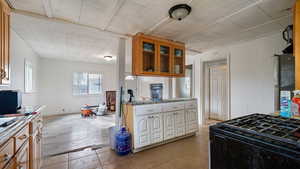 Kitchen with stainless steel fridge, black range with gas cooktop, and light tile patterned floors