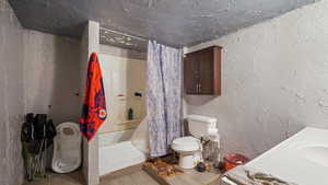 Full bathroom with shower / bathtub combination with curtain, vanity, tile patterned flooring, and toilet