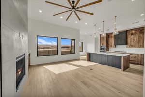 Kitchen featuring a spacious island, light hardwood / wood-style flooring, stainless steel microwave, pendant lighting, and a fireplace