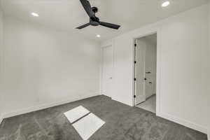 Unfurnished bedroom with ceiling fan and dark carpet