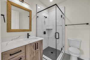 Bathroom featuring vanity, toilet, and a shower with shower door